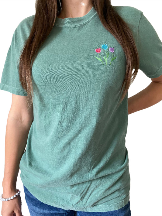 green t-shirt with pink, blue and purple embroidery of tulips